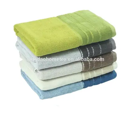 Stack of folded terry towels in green, gray, beige, white, and blue on a white background