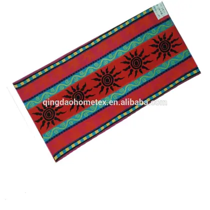Red beach towel with black sun motifs and teal swirl-pattern stripes, shown tilted on a white background