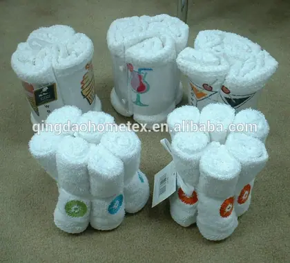 Rolled white towel bundles arranged in flower shapes with cocktail and citrus print designs, one with barcode tag