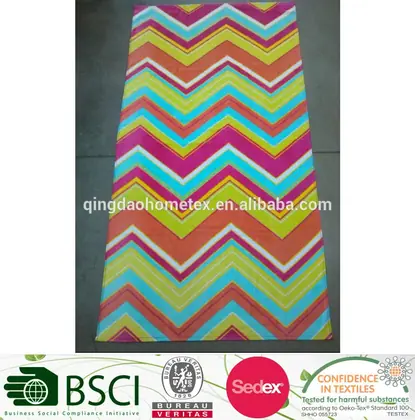 Chevron patterned rug in orange, green, cyan, and magenta on a grey floor.