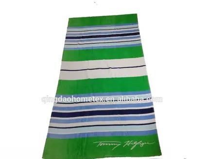 Green striped beach towel with a signature logo at the bottom.