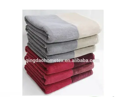 Two stacks of folded two-tone terry towels in grey and cream above red and burgundy, on a white background