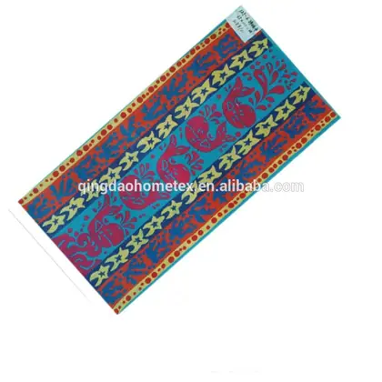 Colorful beach towel with folk-art whale and starfish pattern in teal, red, blue and yellow, laid diagonally on white background