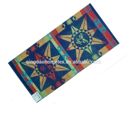 Rectangular beach towel with geometric star pattern in blue, red and yellow, shown diagonally on white background
