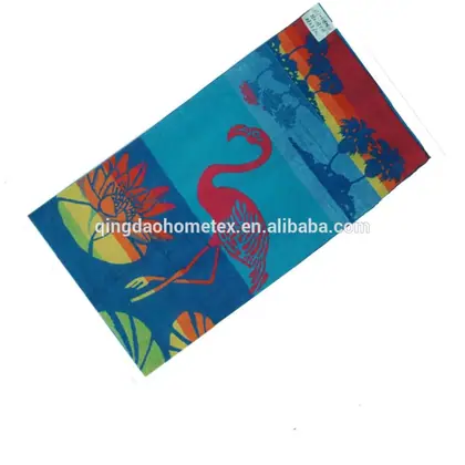 Printed beach towel with flamingo, flowers and stripe pattern, tilted diagonally on white background