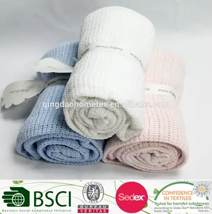 Rolled baby blankets in blue, white, and pink stacked on a white surface