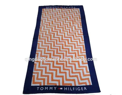 Tommy Hilfiger beach towel with orange chevron pattern displayed vertically with certification logos.