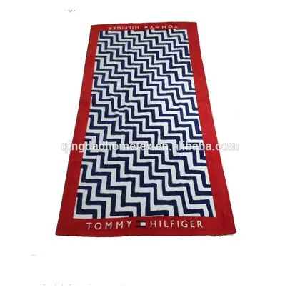 Red beach towel featuring a navy and white chevron pattern with brand text on the borders.