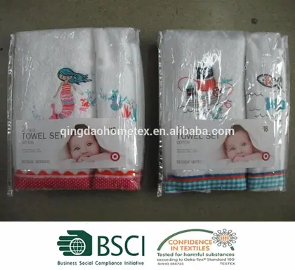 Two packaged towel sets featuring embroidered designs and baby-themed labels sitting on a floor.
