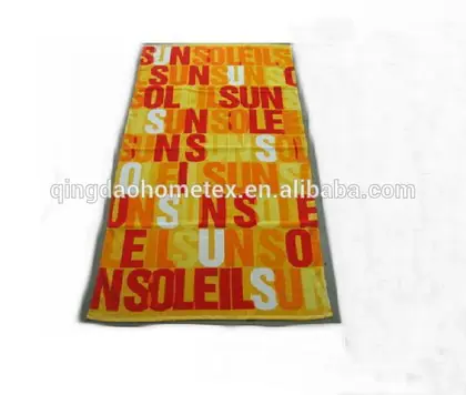 A yellow and orange beach towel featuring the word 'SUN' in various fonts and colors.