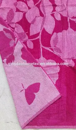 Pink and magenta jacquard towel with floral leaf pattern and butterfly motif on light background