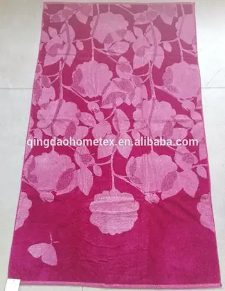 Magenta pink jacquard towel with light pink floral and butterfly pattern laid on a tiled floor