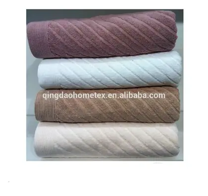 Stack of four folded towels in pink, white, tan and cream colors on a plain surface