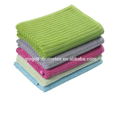 Stack of five ribbed cotton towels in green, gray, pink, cream, and blue on a white background
