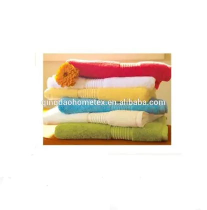 Stack of folded towels in red, white, yellow, blue and green with an orange flower on top