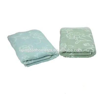 Two folded floral-jacquard towels, one light blue and one sage green, on a white background