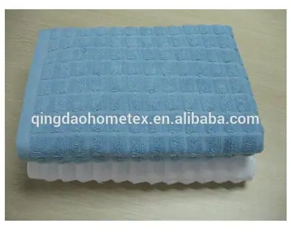 Folded blue waffle-weave towel stacked on top of a white towel on a wooden table surface