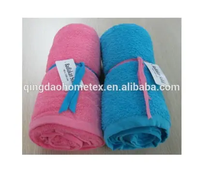 Two rolled terry towels, one pink and one blue, tied with ribbon bows and paper tags, on a light surface
