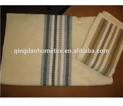 Two cream towels with stripes, one laid flat with blue-gray bands and one folded with brown bands