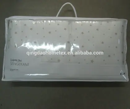 Packaged white pillow set with gold star pattern in clear plastic with handle.