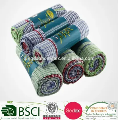 Stack of rolled checkered kitchen towels in teal printed wrappers with certification logos along the bottom