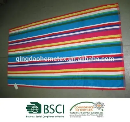 Colorful striped beach towel with multicolored horizontal bands laid flat on a grey floor