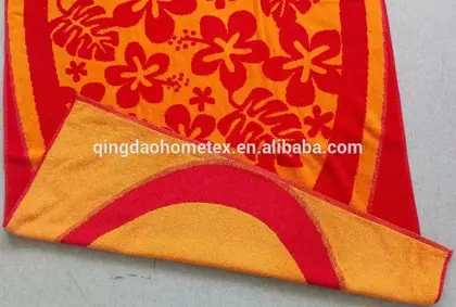 Folded orange and red towels with hibiscus floral print photographed on a gray floor