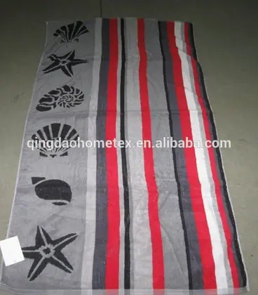 Grey striped beach towel with black printed starfish and seashell motifs, shown flat on a dark floor