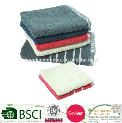Stack of folded waffle-weave towels in gray, navy, red, and cream with certification logos below