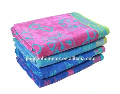 Stack of folded pink and blue patterned beach towels with BSCI and Oeko-Tex certification logos at bottom