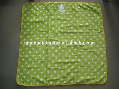 Green baby blanket with white star pattern and yellow trim, flat on dark surface, with website watermark