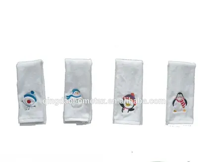 Four white towels with embroidered snowman and penguin winter designs displayed on a white background