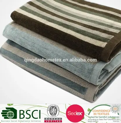 Three folded striped towels stacked in brown, green, and taupe on a white background