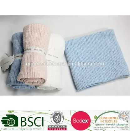Rolled pastel knitted baby blankets in pink, blue and white with a folded blue blanket on white background