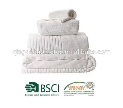 Stack of folded white terry towels and a rolled towel on a white background