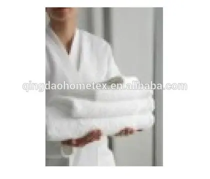 Model in white bathrobe holding a stack of folded white towels