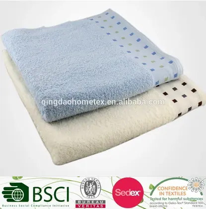 Stack of folded light blue and cream towels with dotted borders on a plain white background
