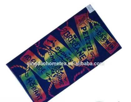 Navy blue beach towel printed with colorful tag designs naming Australian cities, certification logos below