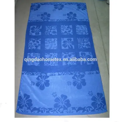 Blue beach towel with floral print in patchwork-style bands, laid flat on a gray floor