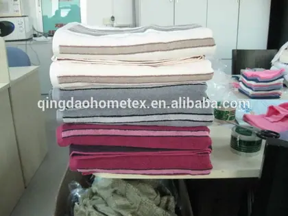 Stack of folded striped towels in beige, white, gray, and pink on a cluttered office desk