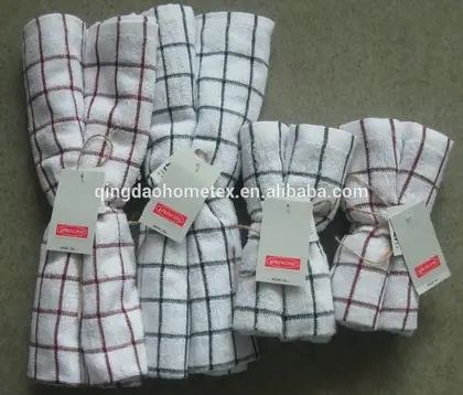 Five folded white kitchen towels with red and black grid patterns and attached tags.