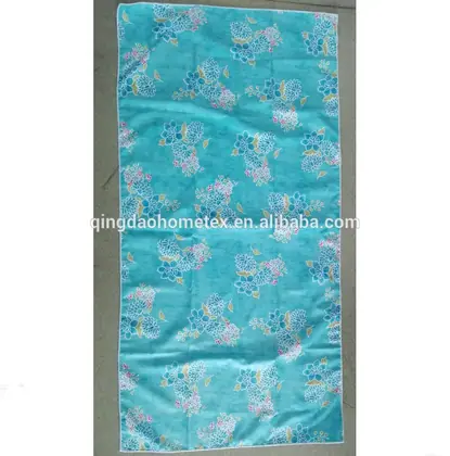 Turquoise towel with blue and pink floral print lying flat on a concrete floor