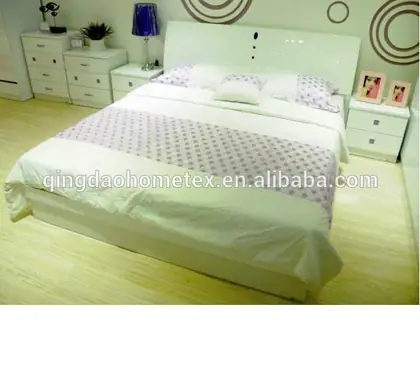 White bedroom set with double bed, nightstands, and chest of drawers in a decorated showroom room