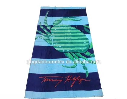 Blue and navy striped beach towel with green crab print and red script logo, shown flat on white background