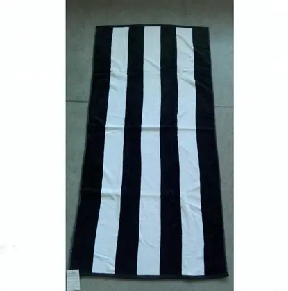 Black and white striped beach towel laid flat on a grey floor