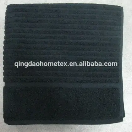 Folded black towel with ribbed texture on a light background