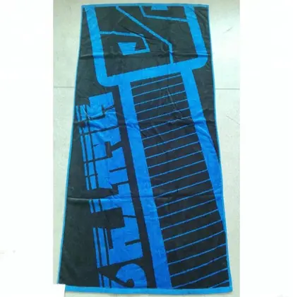 Blue and black printed beach towel laid flat on a tiled floor, photographed at an angle