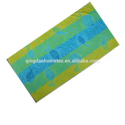 Colorful printed beach towel with blue, green and yellow fish patterns laid flat on a white background
