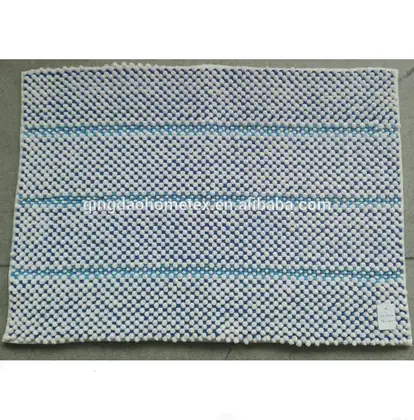 Blue and white chenille bobble bath mat with horizontal striped rows, photographed on a tiled floor