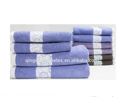 Stacks of folded towels in purple, lavender, and brown with white patterned bands, plus BSCI and Confidence in Textiles logos